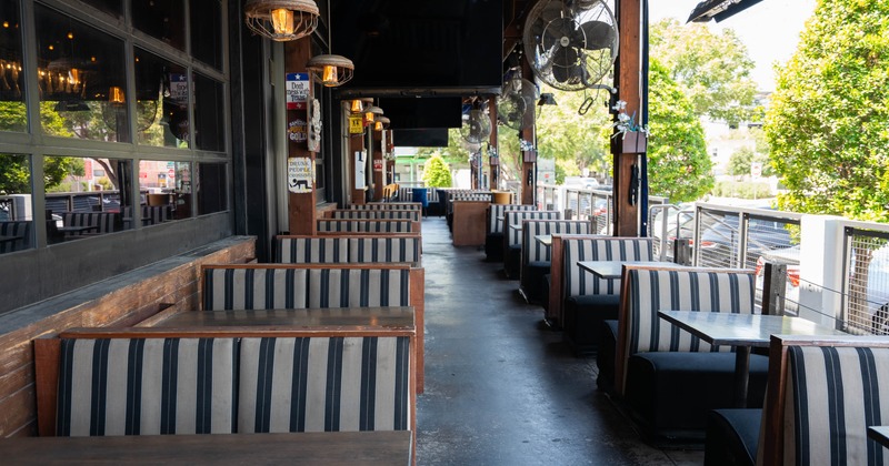 Outdoor patio - wooden booths, striped upholstery & hanging pendant lights.