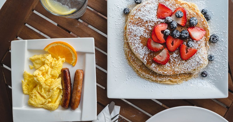 Omelet and sausage plate and a plate with pancakes, top view
