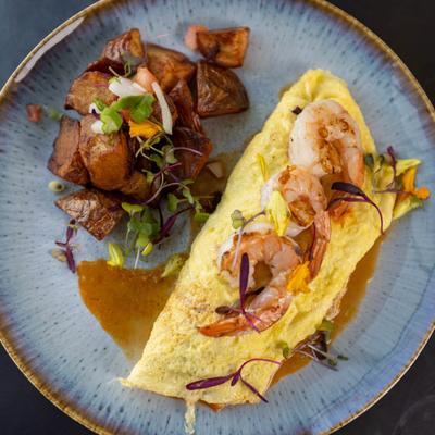 Spicy Tom Yum Omelet topped with shrimp, served with potatoes.