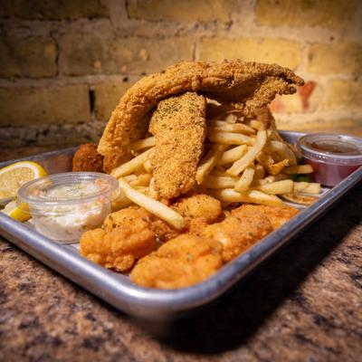 Fried catfish and shrimp platter with French fries, coleslaw, and dipping sauce.