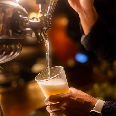 A person pours draft beer into a glass at a bar.