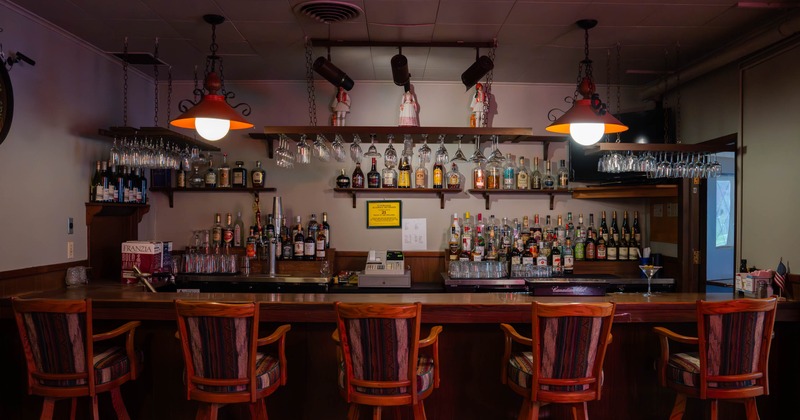 A cozy, well-stocked bar with wooden stools and warm lighting.