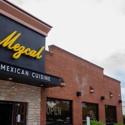 Exterior of Mezcal Mexican Cuisine restaurant with brick walls and yellow signage.