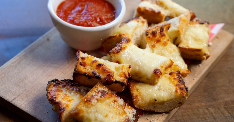 Garlic cheesy bread with a cup of pizza sauce for dipping