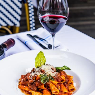 Rigatoni bolognese and glass of red wine.