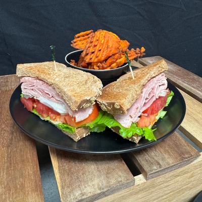 Sliced ham sandwich with sweet waffle fries.
