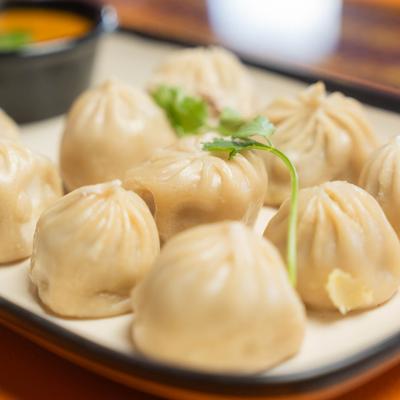Plate of steamed dumplings with a shiny texture, garnished with cilantro.