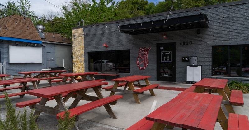 Outdoor dining area with red picnic tables in front of the restaurant