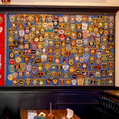 Police department uniform patches mounted on a blue background above a booth.