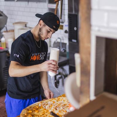Employee preparing a pizza.