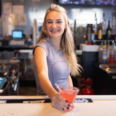 Bartender holding a cocktail at a bar.