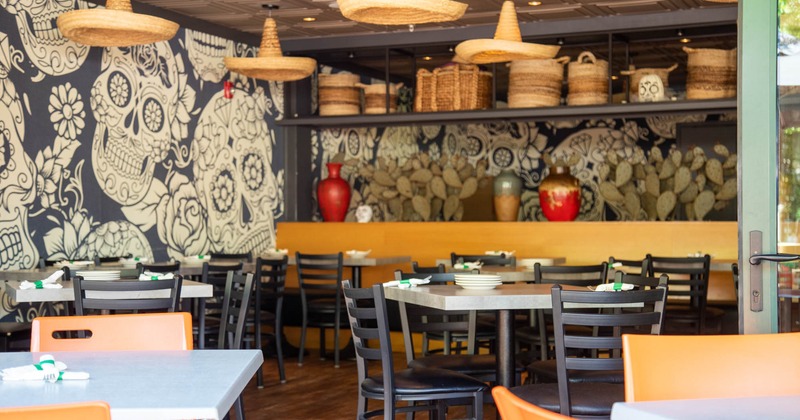 Decorated dining area, wall mural with traditional skull motifs, hanging sombrero lanterns