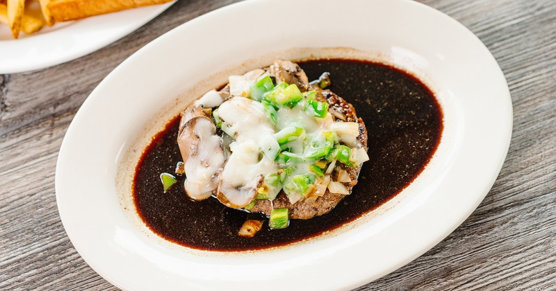 Monte Carlo Steak served in a dark gravy, topped with melted cheese and mushrooms