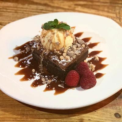 Nutella brownie dessert topped with ice cream, caramel sauce, and fresh raspberries.