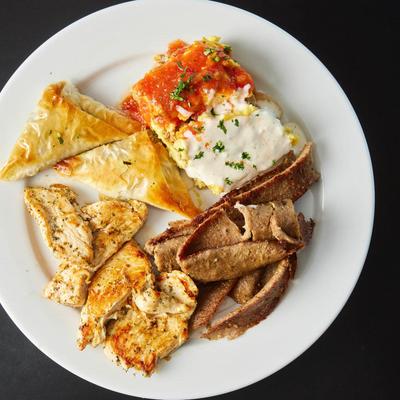 Moussaka, Spanakopita, Gyro Meat, and Chicken Souvlaki served on a plate.