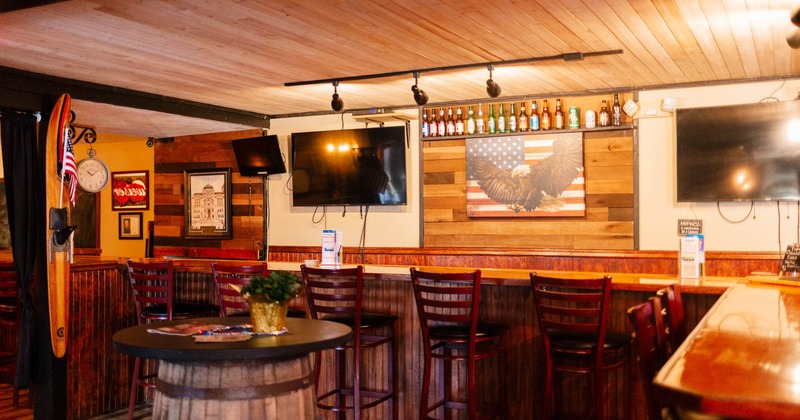 Interior, seating area with bar stools, TVs on the wall