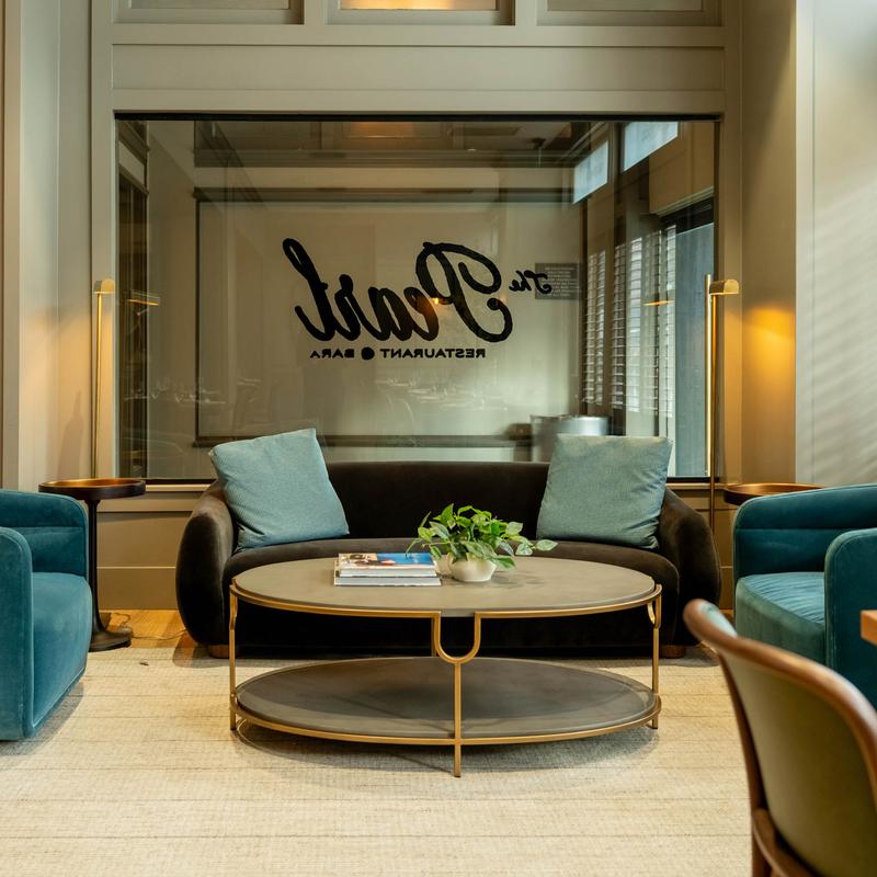 Lounge seating area with sofa, armchairs, table and sign in the background.