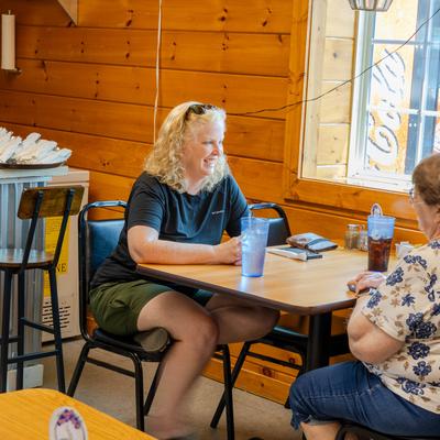 Two customers are sitting at a table in dining area, talking and enjoying drinks.