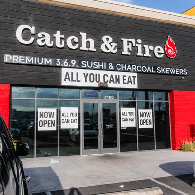 Catch & Fire restaurant storefront with dark siding, signage, and large windows.