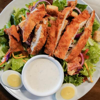 Crispy chicken strips over salad with creamy dressing.