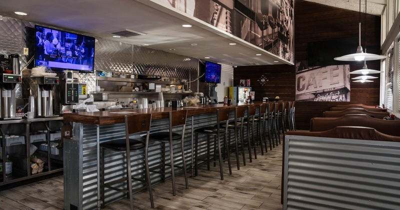 Interior, bar area, wooden top bar with stools, prep station in the back, booths on the right