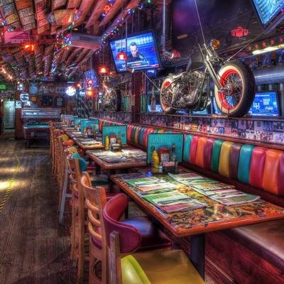 Colorful diner with vibrant striped seating, vintage decor, and motorcycles displayed above booths