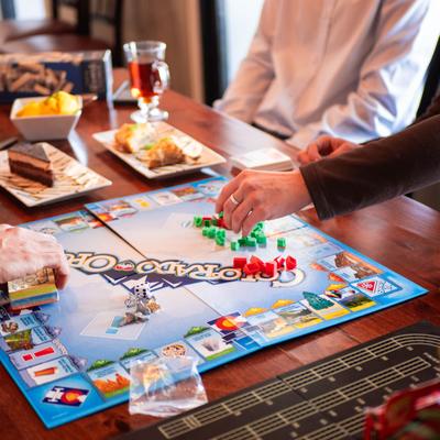 People playing a board game at a restaurant table with served desserts.
