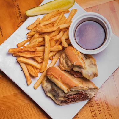 French dip sandwich with fries and meat broth for dipping.