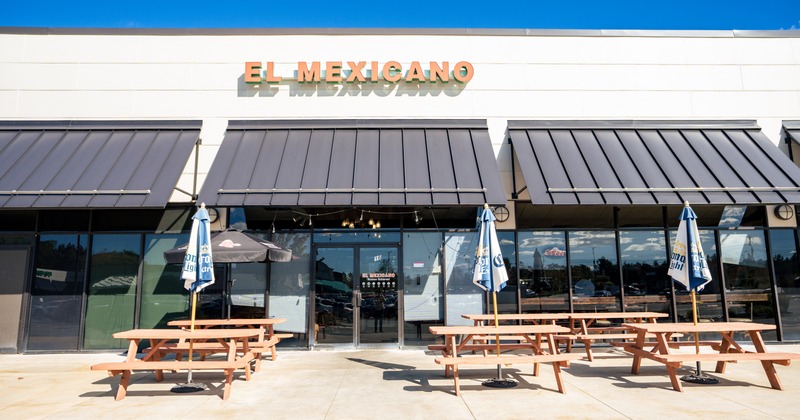 Exterior, front view to restaurant, benches and tables in front, entrance, sign above