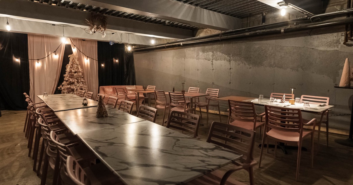 Interior with tables, chairs, dim lights, and a Christmas tree