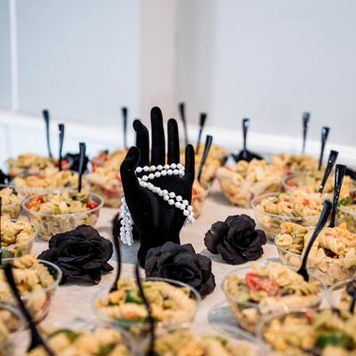 Food in bowls on a table, black hand with pearls and black roses decoration.