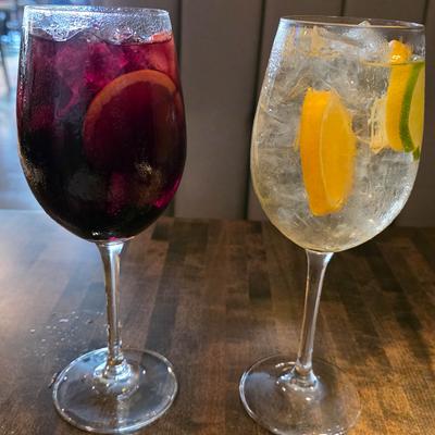 Two wine glasses filled with red sangria and white sangria garnished with citrus.