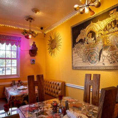 Dining area with vibrant yellow walls, unique wooden chairs and a large framed artwork.