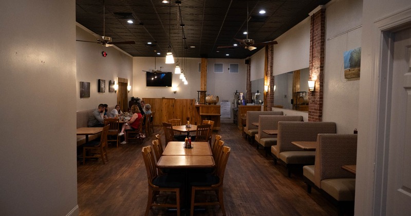 Dining area with booths, wooden tables, and pendant lights