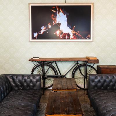 Black leather sofas, a vintage bicycle console table, and a framed picture of a fireplace.