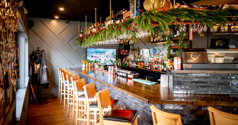 Interior, bar area, wooden top bar with padded wooden stools, drink shelves and espresso machine