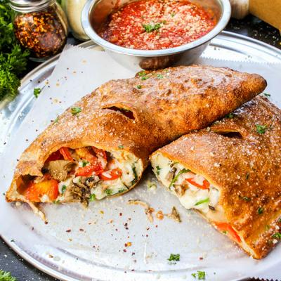 Calzone with cheese, mushrooms, spinach, peppers, and marinara dipping sauce