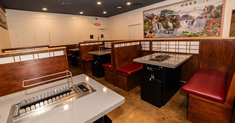 Interior with booths, grill tables and large landscape painting on the wall