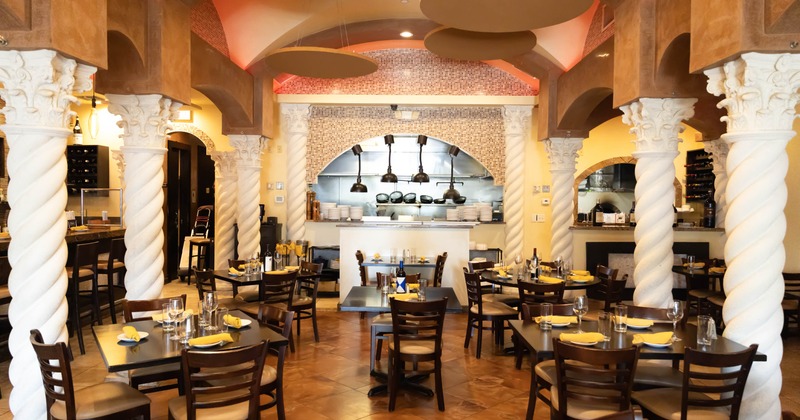 Interior, ornate columns, warm lighting, and an open kitchen visible in the background