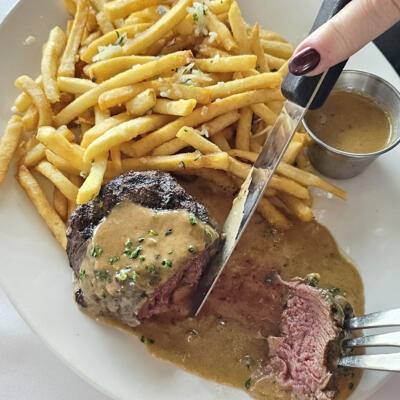Peppercorn steak filet, cutting it like butter, with frits on the side.
