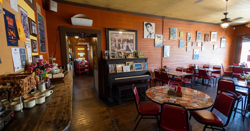 Interior of a rustic cafe featuring orange walls, wooden furniture, round tables