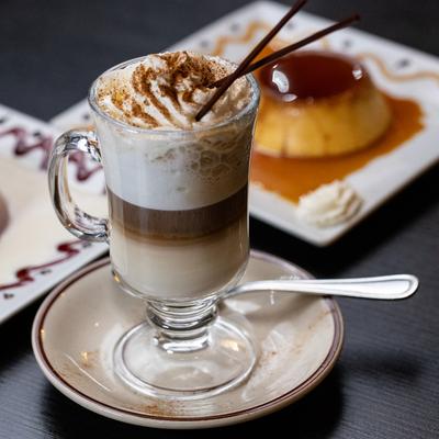 Layered cappuccino with whipped cream, chocolate sticks, and a sprinkle of cinnamon.