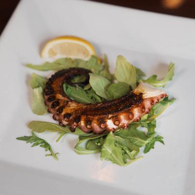 Grilled octopus on a bed of arugula.