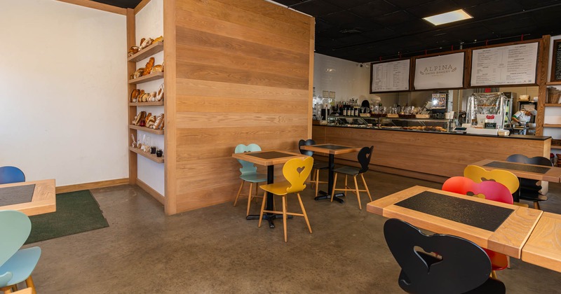 Interior with a counter, wooden tables, and colorful chairs