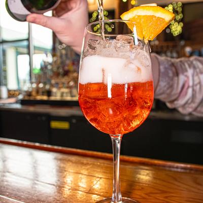Aperol Spritz being topped with sparkling wine from the bottle.