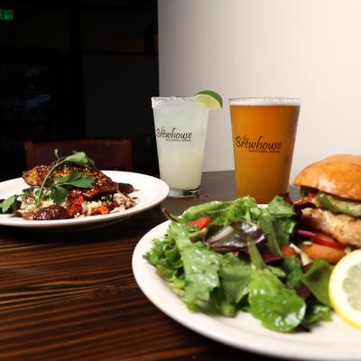 plate of Grilled salmon and plate of Grilled Chicken sandwich with house salad , Beer and margarita.