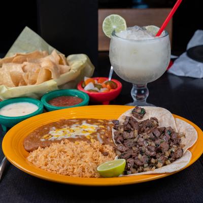 Beef taco plate, accompanied with chips, salad, dipping, and margarita cocktail.