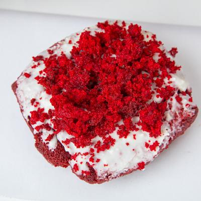 Red velvet donut topped with white cream and red velvet cake.