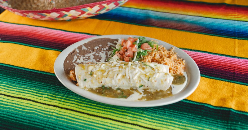 Burrito smothered in green salsa, with rice, beans, and salad