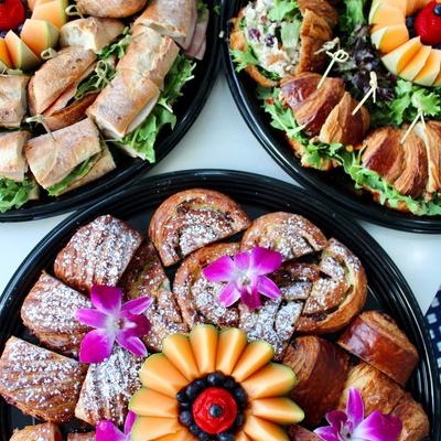 Platters with different types of sandwiches arranged with flower garnish and fruit, top view